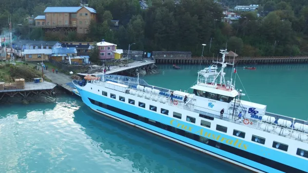 Ferry Crux Australis atracado en el puerto de Puerto Yungay, con edificios coloridos y vegetación patagónica al fondo.