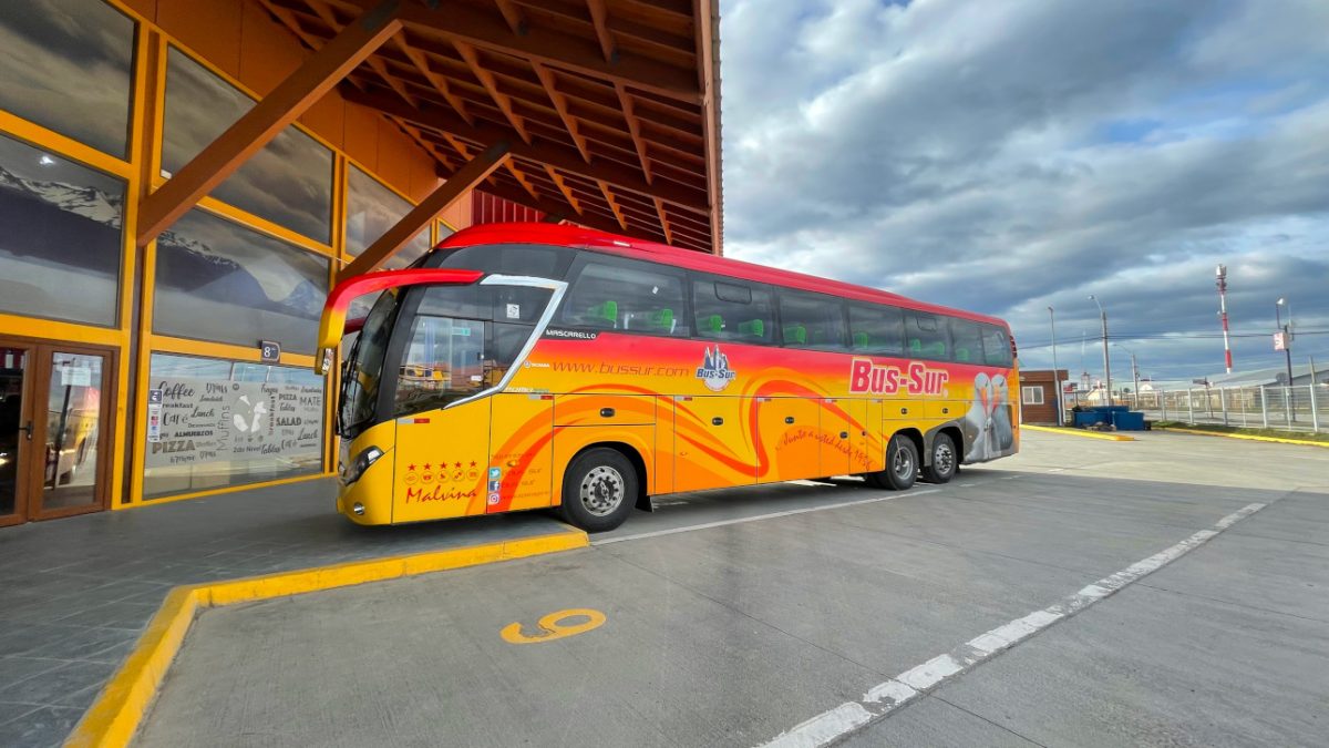 Travelers collecting their luggage from the underside compartment of a Bus Sur coach.