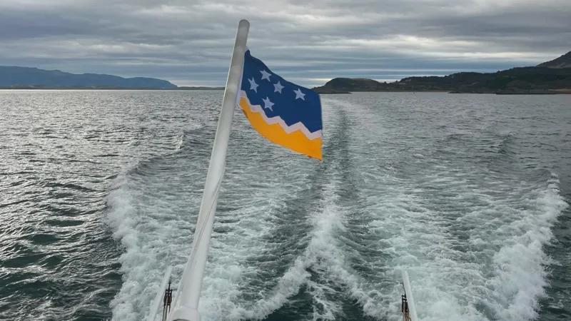 Um grupo de turistas usando coletes salva-vidas em um barco se aproximando de uma grande geleira.