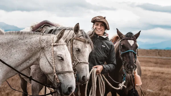 A group of riders following a guide through the rolling hills of the Magallanes region.