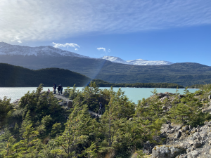 Visitantes en el mirador del Glaciar Serrano contemplan el lago turquesa rodeado de bosque y montañas nevadas en la