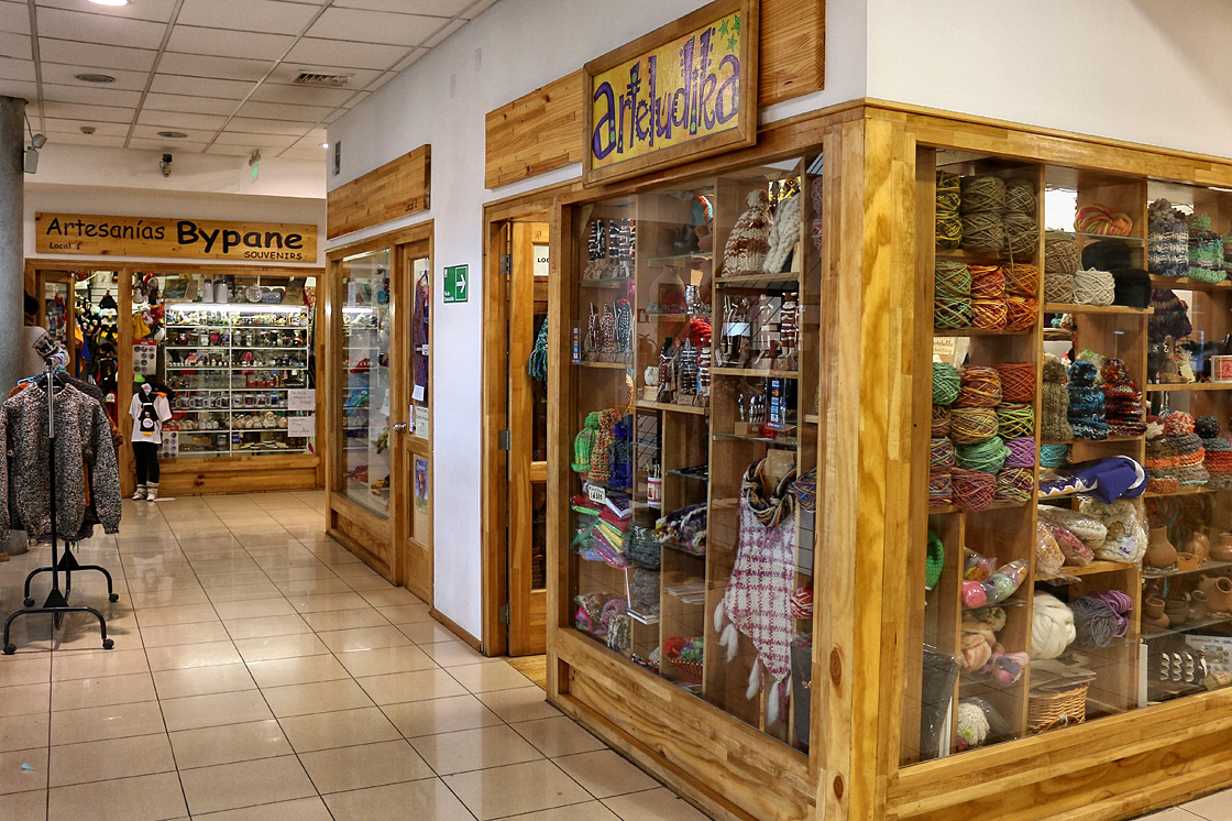 O interior vibrante do mercado de Punta Arenas, com barracas que vendem frutos do mar e artesanato local.