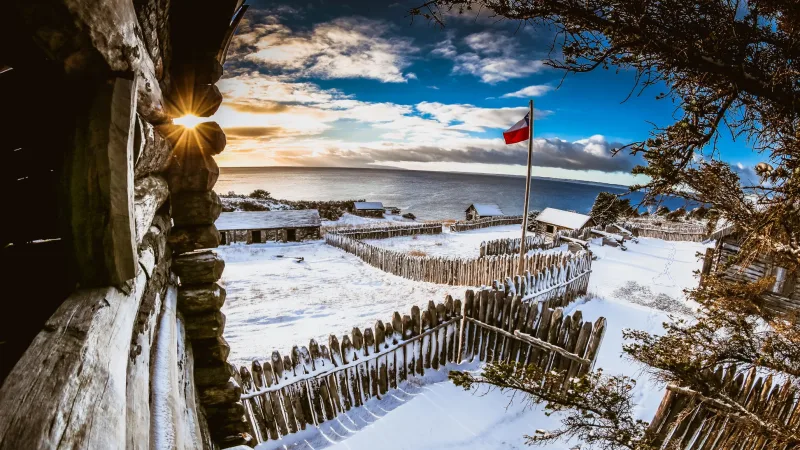 The wooden buildings of Fuerte Bulnes covered in a light layer of winter snow.