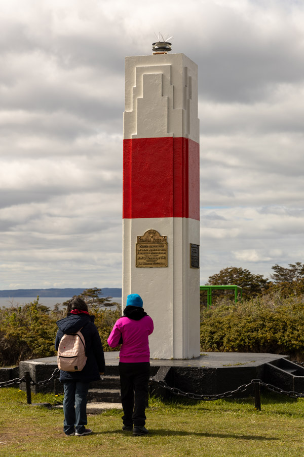Waves crashing against the rocks near the O'Higgins lighthouse at sunset.