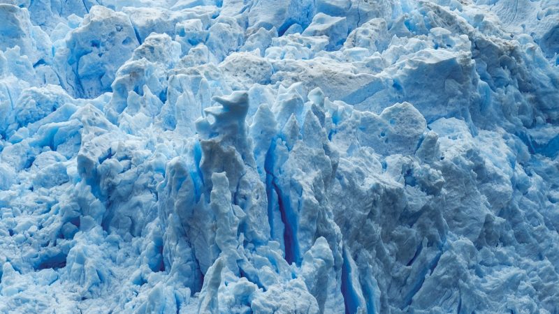Embarcación con turistas frente a la imponente pared de hielo azul del Glaciar Sarmiento en la Patagonia chilena.