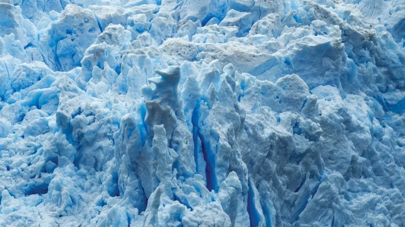 Embarcación con turistas frente a la imponente pared de hielo azul del Glaciar Sarmiento en la Patagonia chilena.