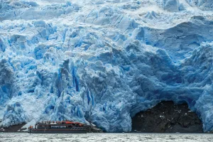 Embarcación con turistas frente al imponente muro de hielo azul del glaciar Sarmiento en Patagonia